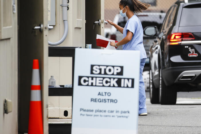 Six states have an agreement to acquire fast-result antigen tests for the coronavirus. Here, a medical worker collects a sample after a patient self-administers a nasal swab test.