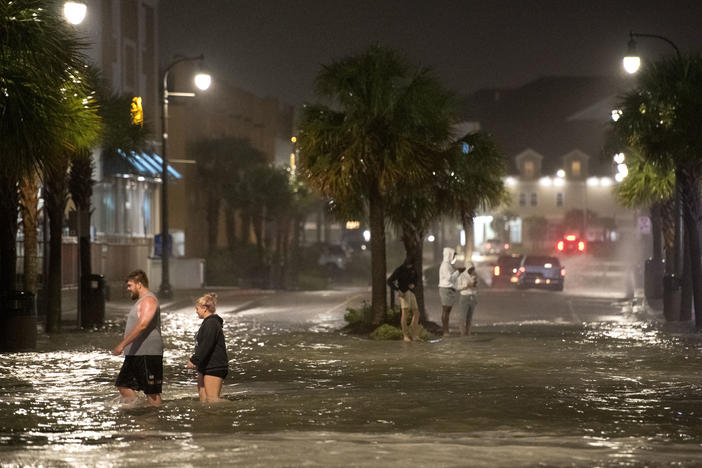 Hurricane Isaias made landfall near Ocean Isle Beach, N.C., near the border with South Carolina. Pictured are people walking through floodwaters in Myrtle Beach, S.C.