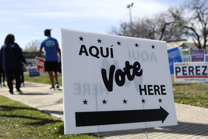 Pedestrians pass signs near a polling site in San Antonio in February.