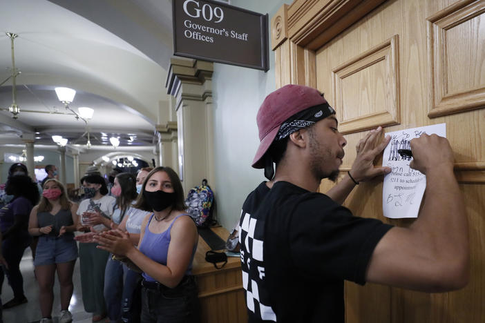 Matthew Bruce of Des Moines, Iowa, signs a note during a Black Lives Matter demonstration outside Iowa Gov. Kim Reynolds' office in June. The Republican governor has signed an executive order restoring voting rights to people convicted of a felony.