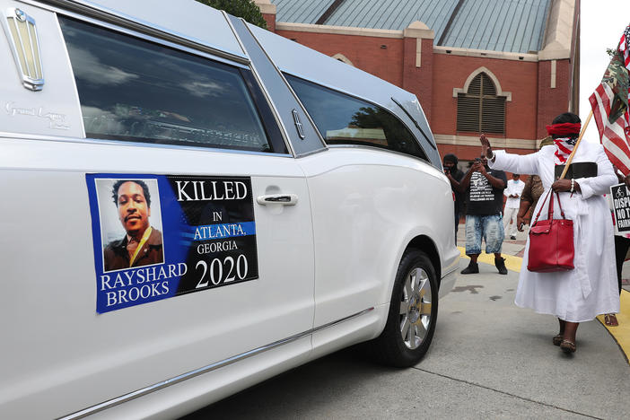 People gather near a hearse carrying Rayshard Brooks' body after his June 23 funeral at Ebenezer Baptist Church in Atlanta.