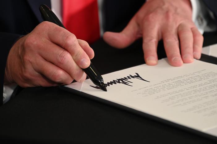 President Trump signs executive actions regarding coronavirus economic relief during a news conference in Bedminster, N.J., on Saturday. A number of lawmakers are criticizing the measures' substance and constitutionality.