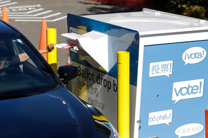 A voter inserts a ballot in a drive-up drop box last week in Renton, Wash., in that state's primary. With more states expanding absentee voting due to the pandemic, the use of drop boxes is growing and leading to legal challenges from some Republicans.