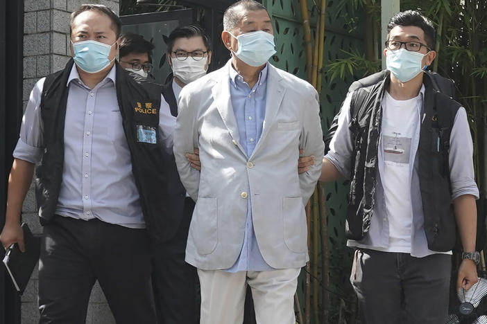 Hong Kong media tycoon Jimmy Lai, center, is arrested by police officers at his home in Hong Kong on Monday. Hong Kong police arrested Lai and raided the publisher's headquarters in the highest-profile use yet of the new national security law Beijing imposed on the city after protests last year.