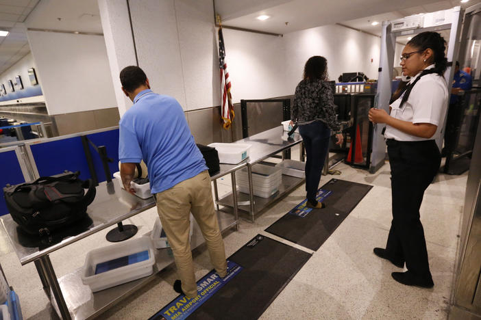 A Transportation Security Administration officer watches as travelers put their items through an X-ray machine in 2017 at Miami International Airport. The TSA says it's finding significantly more firearms in carry-on luggage despite a huge drop in air travel.