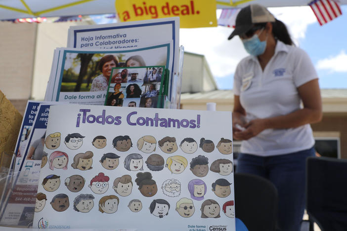 U.S. Census Bureau worker Marisela Gonzales stands by a display of books and flyers about the 2020 census at a walk-up counting site in Greenville, Texas, in July. The bureau's employees are under a time crunch to try to complete the national head count after the agency announced that counting will end a month early.
