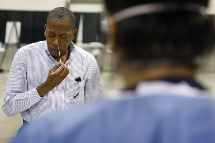 Clark County Commission Vice Chairman Lawrence Weekly swabs his nose while giving a coronavirus test to himself during a tour of setup at a temporary coronavirus testing site in Las Vegas on Aug. 3.