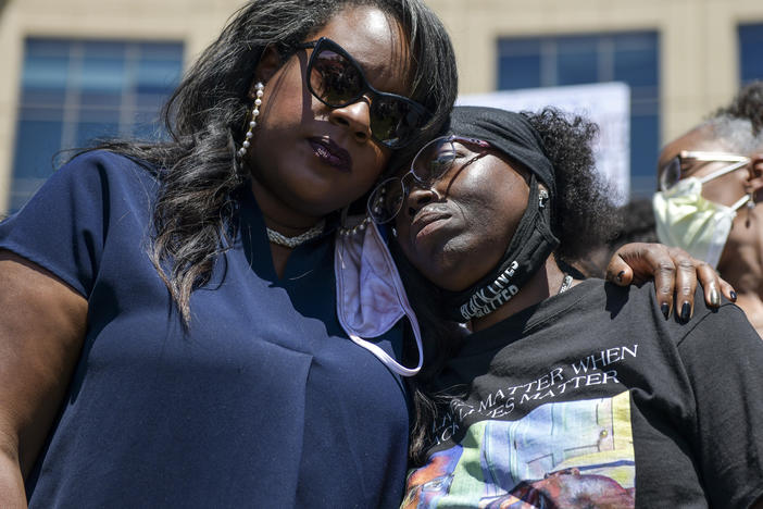 Elijah McClain's mother, Sheneen McClain (right), gets a hug from <strong></strong>Colorado state Rep. Leslie Herod in June as they stand with protesters outside the Aurora, Colo., police headquarters. On Tuesday, Sheneen McClain and Lawayne Mosley filed a federal civil rights lawsuit in their son's death.