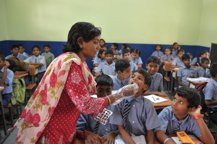 A teacher gives a deworming tablet to a student during National Deworming Day at a high school in Hyderabad, India, in 2017.