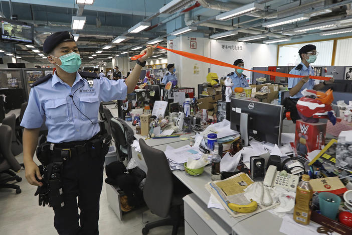 Hong Kong police officers search the newsroom of the <em>Apple Daily</em> newspaper Monday after arresting the paper's publisher, Jimmy Lai.