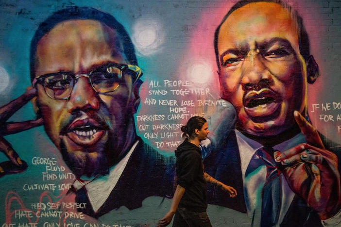 A man walks past a mural of Malcom X and Martin Luther King Jr. in London.