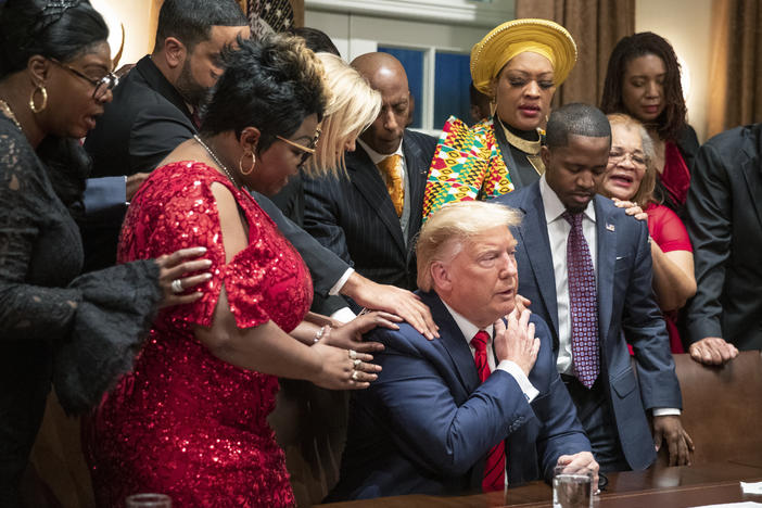 Black leaders say a prayer with President Trump as they end a meeting in the Cabinet Room of the White House in February.