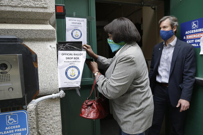 A voter places a ballot in a secure box in Providence, R.I., in June for the state's presidential primary. The U.S. Supreme Court says the state can suspend its witness or notary requirement to vote by mail in the fall elections.