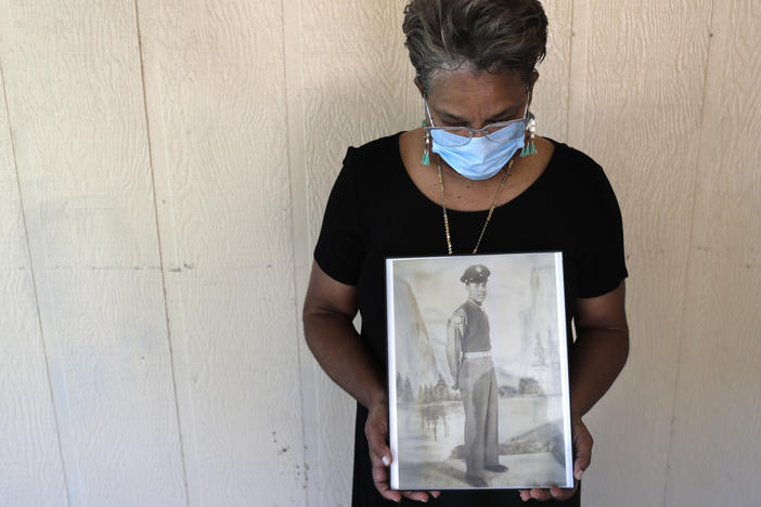 Belvin Jefferson White poses with a portrait of her father, Saymon Jefferson, who died from COVID-19, in Baton Rouge, La., in May.