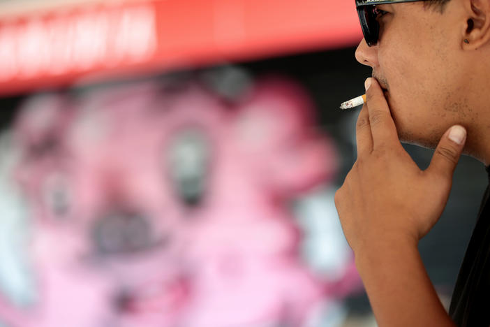 A man smokes in the street in Madrid on Friday after Spain's health minister announced curbs on smoking outdoors in an effort to contain a resurgence of COVID-19.