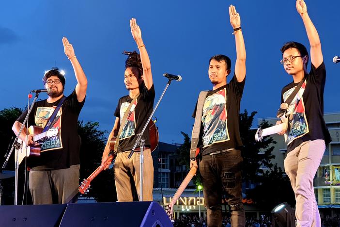 Members of a musical group at Sunday's pro-democracy demonstration in Bangkok make a gesture of resistance popularized by <em>The</em> <em>Hunger Games </em>movies.