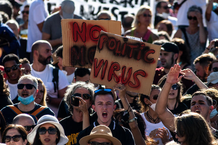 People holding placards and shouting slogans protest Sunday in Madrid against the mandatory use of face masks and other measures adopted by the Spanish government to prevent the spread of the coronavirus.