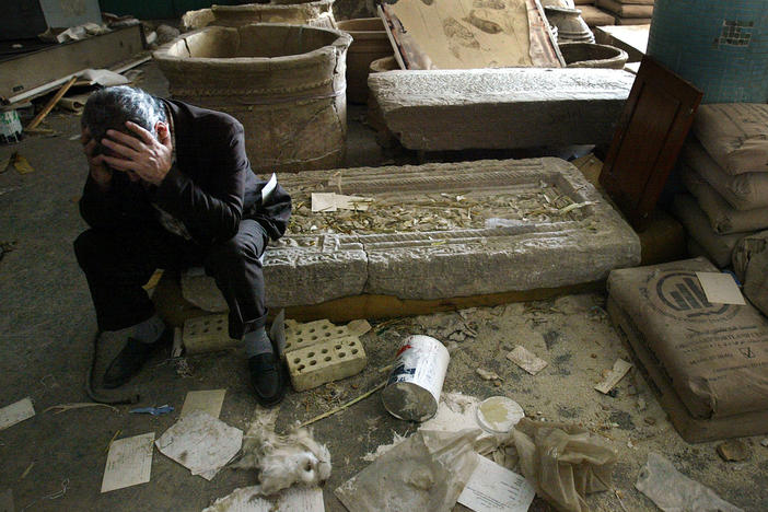 Iraqi National Museum Deputy Director Musin Hassan holds his head in his hands as he sits amid destroyed artifacts in the Baghdad museum in 2003.
