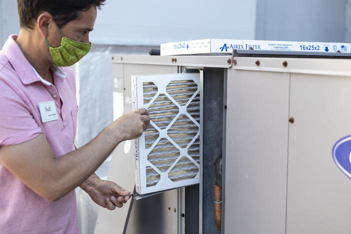 Mark Marston slides a MERV 13 air filter into the HVAC system outside Basics Fitness Center in Portland, Maine, on July 21. The gym bought these filters and made other changes to its ventilation, including bringing in more outside air, to help reduce the spread of the coronavirus.