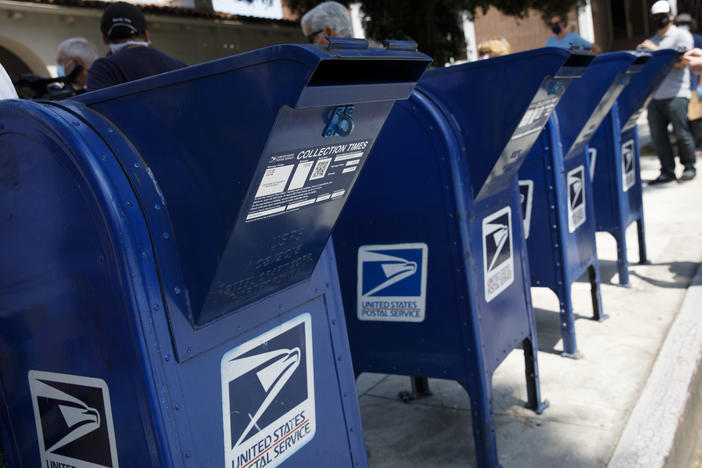 A customer deposits mail into a U.S. Postal Service mail collection box this week in Burbank, Calif.