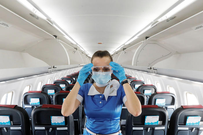 A flight attendant adjusts protective glasses. There has been little documentation about COVID-19 transmission on planes.