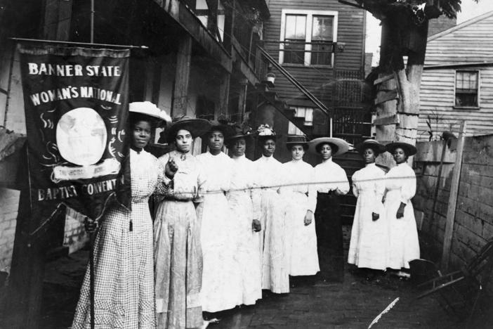 Nannie Helen Burroughs holds a banner reading, "Banner State Woman's National Baptist Convention" as she stands with other African American women, photographed between 1905 and 1915. Burroughs was an educator and activist who advocated for greater civil rights for African Americans and women.