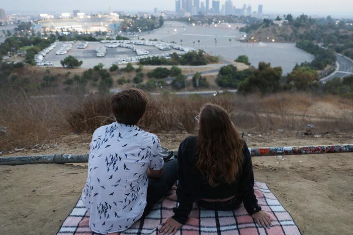 People gather for a picnic on a hillside overlooking Dodger Stadium in Los Angeles during a game Saturday. Spectators are currently not allowed to attend Major League Baseball games in order to prevent the spread of the coronavirus.