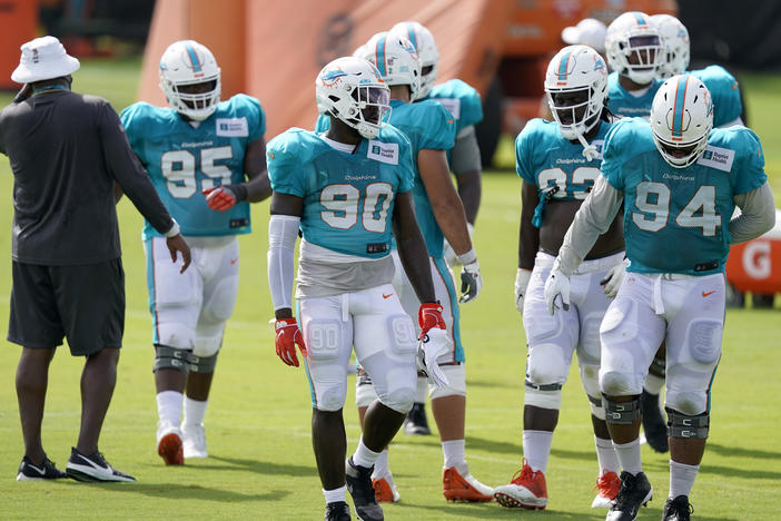 Players for the Miami Dolphins take a break between practice drills during training camp last Friday. When the regular season begins, they'll be playing in front of a smaller-than-normal crowd due to coronavirus restrictions.