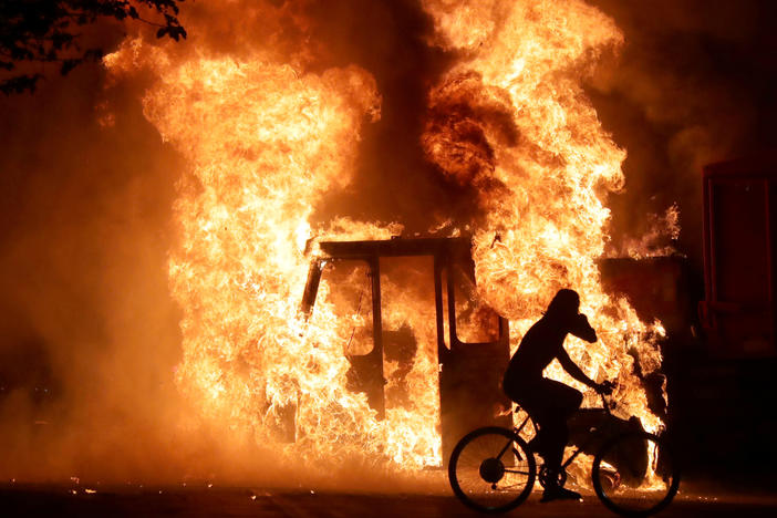 A man on a bike rides past a city truck on fire outside the Kenosha County Courthouse in Kenosha, Wis., during protests following the police shooting of Jacob Blake, a Black man, on Sunday.