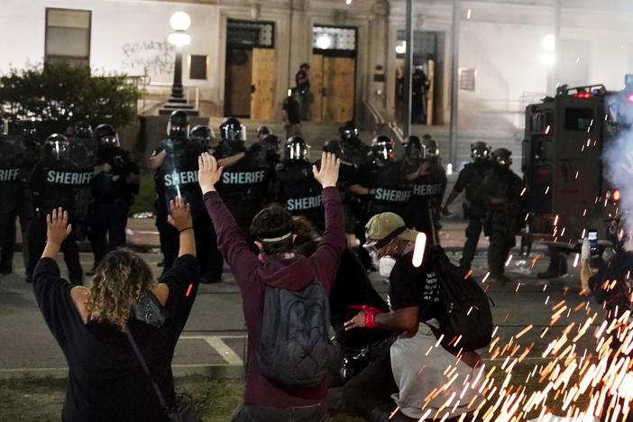 Police attempt to push back protesters outside the Kenosha County Courthouse late Monday in Kenosha, Wis. Protests continued for a second night after the police shooting of Jacob Blake.