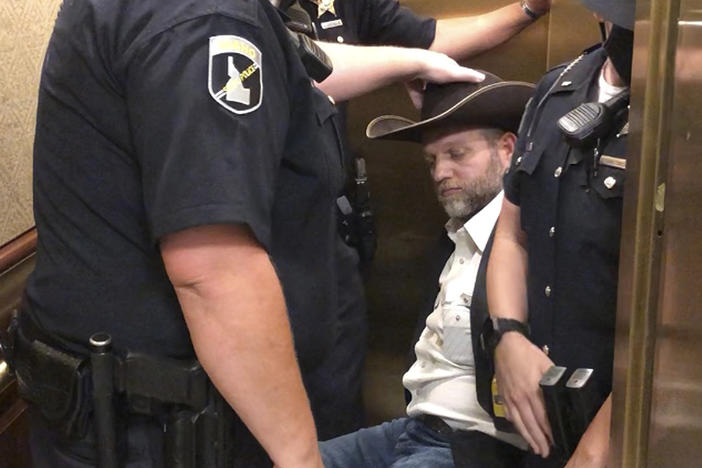 After he refused to stand when asked, anti-government activist Ammon Bundy was wheeled into an elevator in a chair, following his arrest at the Idaho Statehouse in Boise on Tuesday.