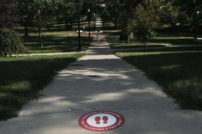 A sign on the ground at The Ohio State University reminds students to practice social distancing. The university has issued more than 200 interim suspensions to students linked to off-campus parties.