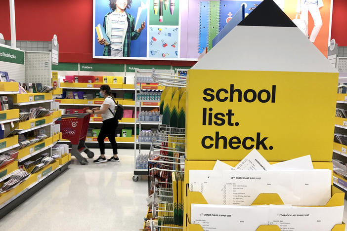 A shopper walks past shelves of school supplies at a Target store in San Rafael, Calif. Preparing for both in-person and virtual learning has families budgeting for new school supplies and bigger purchases.