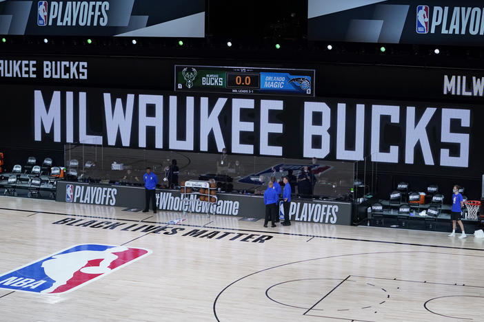 Officials stand beside an empty court at the scheduled start of an NBA playoff game on Wednesday. The Milwaukee Bucks didn't take the floor in protest against racial injustice and the shooting of Jacob Blake.