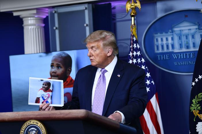 President Trump holds a photo of LeGend Taliferro, a boy killed in Kansas City, Mo., during a White House news conference.