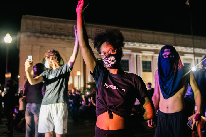 Demonstrators raise their fists in the air on Tuesday in Kenosha, Wis. It was the third night of protests in the city following the police shooting of Jacob Blake on Sunday.