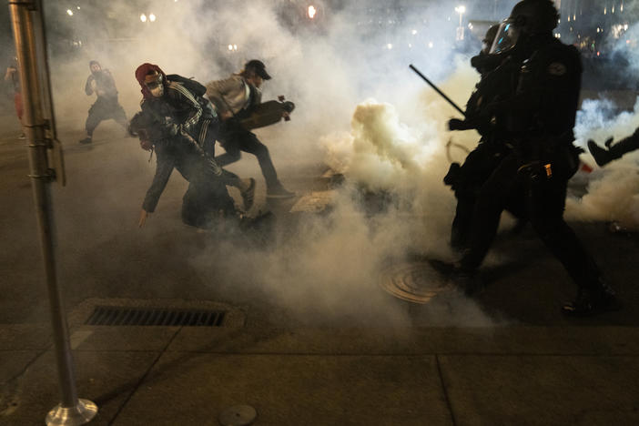 Protesters scramble to get away from approaching police firing tear gas and impact munitions to disperse protesters in downtown Portland during 4th of July demonstrations against systemic racism and police violence.
