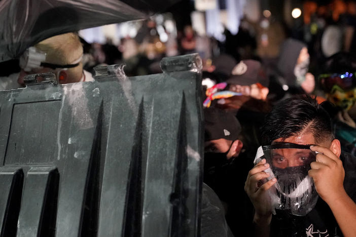 A protester takes cover during clashes outside the Kenosha County Courthouse late Tuesday in Kenosha, Wis.