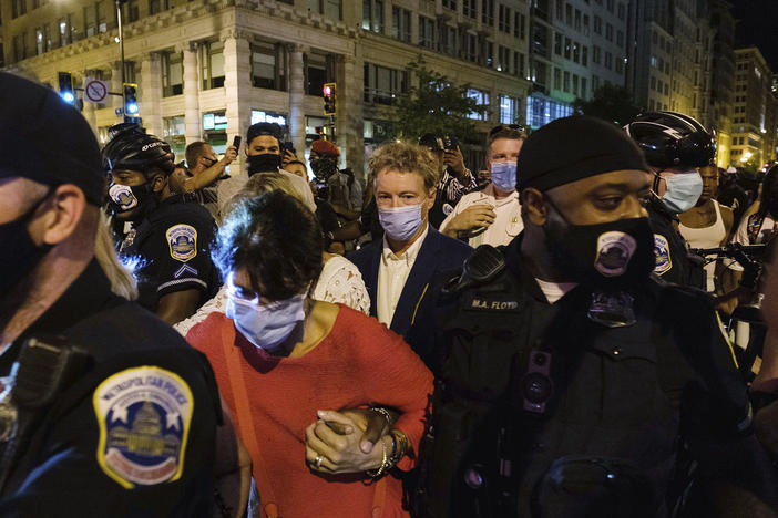 Sen. Rand Paul, R-Ky., center, and others receive a police escort upon leaving President Trump's acceptance speech Thursday night at the White House. A crowd surrounded Paul and his wife, demanding that the senator acknowledge  Breonna Taylor.