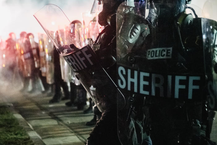 Law enforcement holds a line Tuesday in Kenosha, Wis. The union representing police officers in Kenosha says Jacob Blake, who was shot multiple times at close range and severely wounded by a police officer, was armed with a knife.