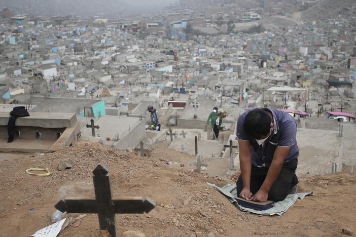A relative prays at the Mártires 19 de Julio Cemetery on the outskirts of Lima, Peru, on Aug. 20. Peru has one of the world's highest per capita coronavirus-related death tolls, according to Johns Hopkins University.