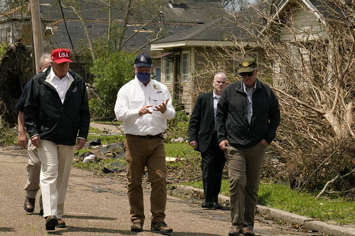 President Trump listens to Louisiana Gov. John Bel Edwards, center, as he tours damage from Hurricane Laura, in Lake Charles, La.