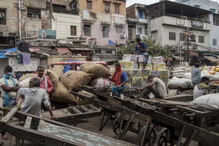 Workers and day laborers gather outside shuttered stores Monday in New Delhi. Once the world's fastest-growing major economy, India posted its steepest decline in gross domestic product in 24 years.