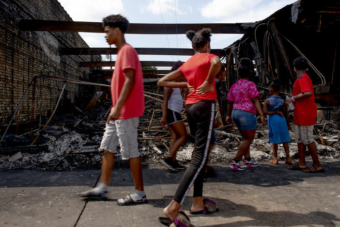 People pass by a destroyed building in Kenosha, WI.