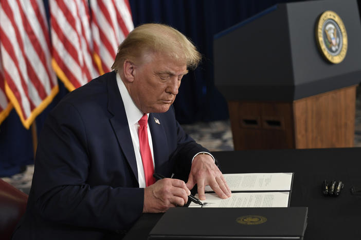 President Trump signs one of four executive orders addressing the economic fallout from the pandemic in Bedminster, N.J., on Aug. 8. The Trump administration has given employers the option to stop collecting payroll taxes, but workers may have to repay the money next year.