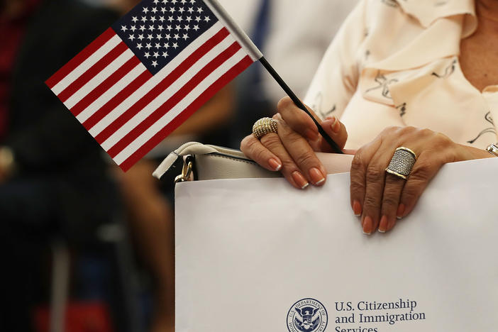 An attendee holds an American flag at a U.S. Citizenship & Immigration Services naturalization ceremony in Miami, Fla. in Aug. 2018. The Trump administration is considering expanding its collection of biometric data as part of the immigration process.