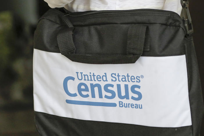 A U.S. Census Bureau worker carries a briefcase while knocking on the door of a home in August in Winter Park, Fla.