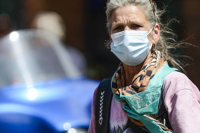 A woman crosses the street as motorcyclists ride through Deadwood, South Dakota during the Sturgis Motorcycle Rally. Despite the pandemic this years rally drew nearly half a million attendees.