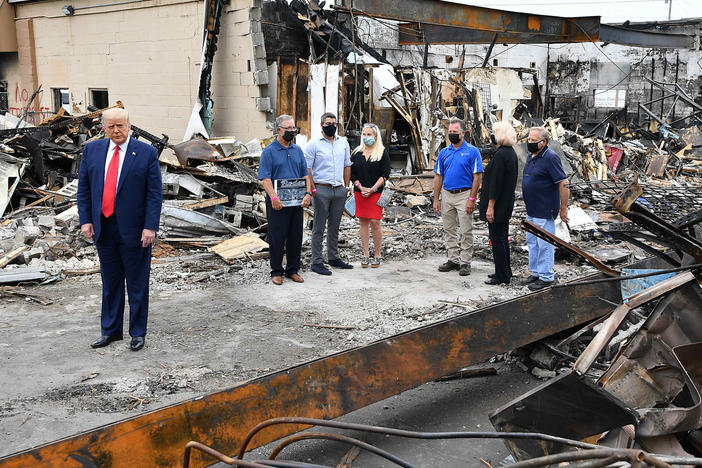 President Trump tours an area affected by civil unrest in Kenosha, Wis., on Tuesday. While there, he attacked Democratic leaders in other nearby big cities, saying they aren't doing enough on crime.