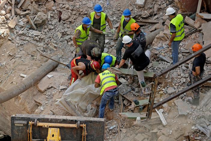 Rescue workers dig through the rubble of a badly damaged building in Lebanon's capital, Beirut, searching for possible survivors a month after a massive blast at the nearby port.